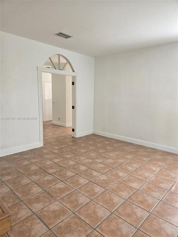 An empty room with tan tile flooring and an arched doorway leading to another space — 4361 Dogwood Circle, Weston FL 33331, WESTON, FL