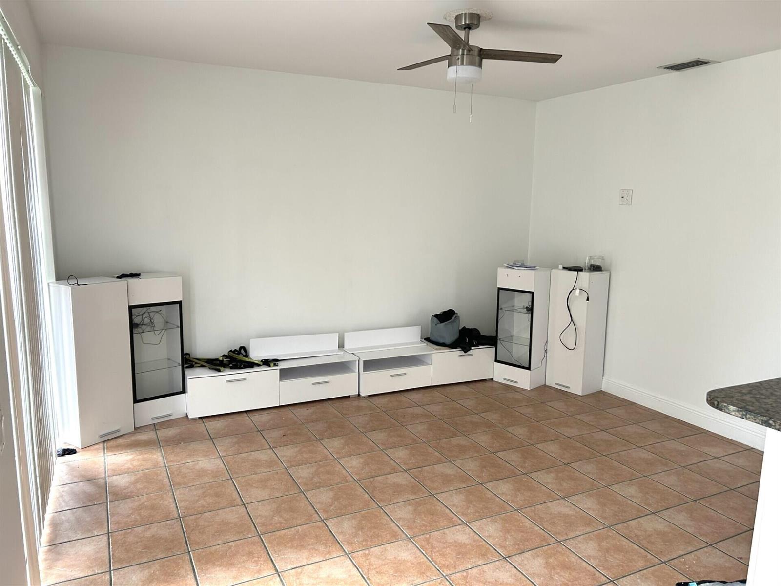 An empty room features white modular storage cabinets, tile flooring, and a ceiling fan — 4361 Dogwood Circle, Weston FL 33331, WESTON, FL