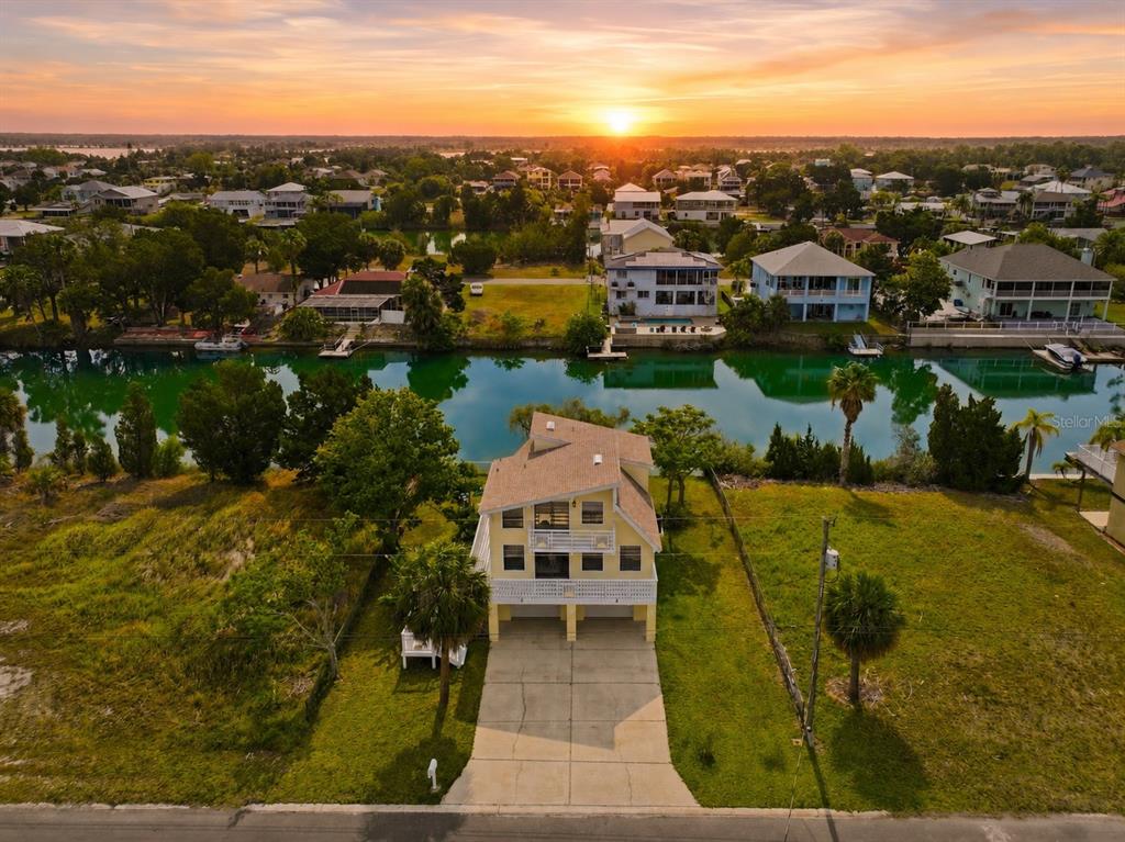 A yellow, elevated two-story house with a concrete driveway and a palm tree — 3294 GARDENIA DRIVE, HERNANDO BEACH, FL