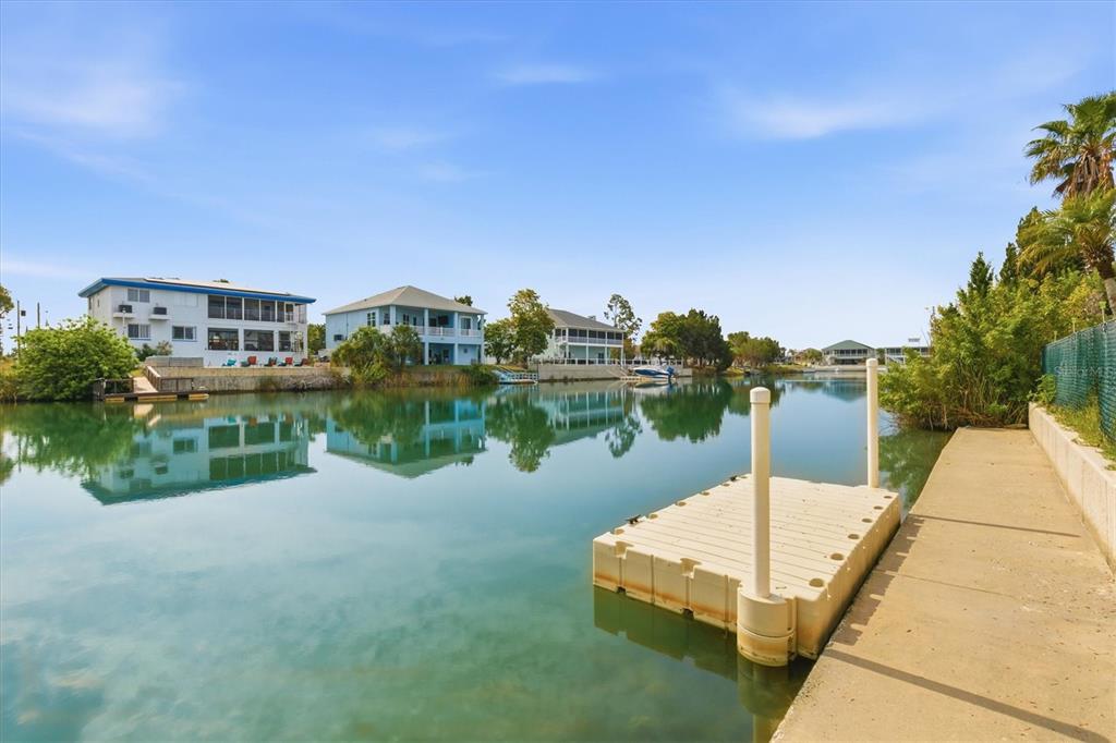 An aerial view of a yellow elevated house situated on a canal at sunset — 3294 GARDENIA DRIVE, HERNANDO BEACH, FL