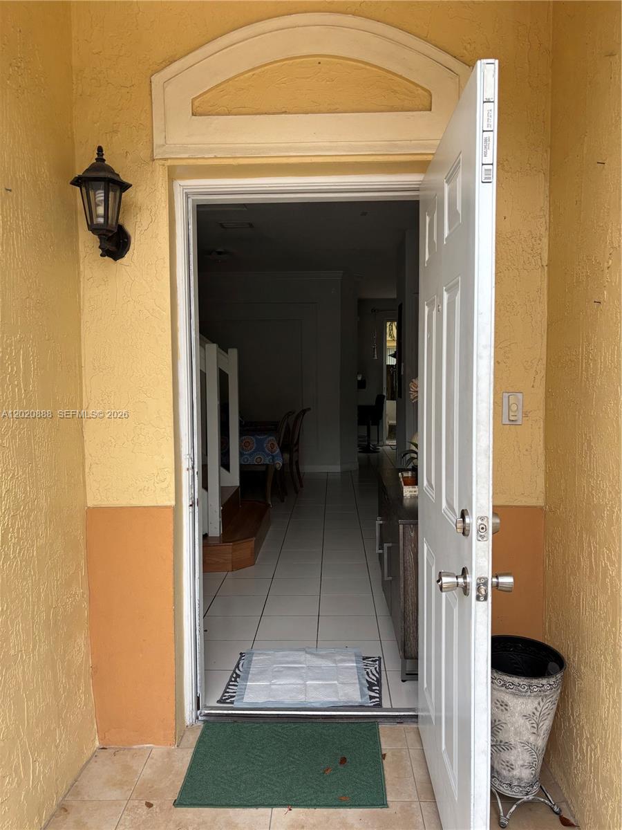 An open front door reveals a tiled entryway leading into a dining area — 6920 NW 177th St # Q101, Hialeah FL 33015, HIALEAH, FL