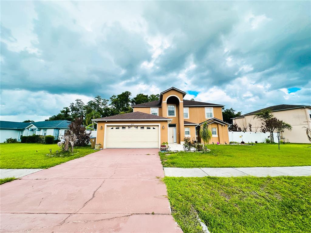 A two-story tan house with a two-car garage and a pink concrete driveway — 577 PINEHURST COVE, KISSIMMEE, FL