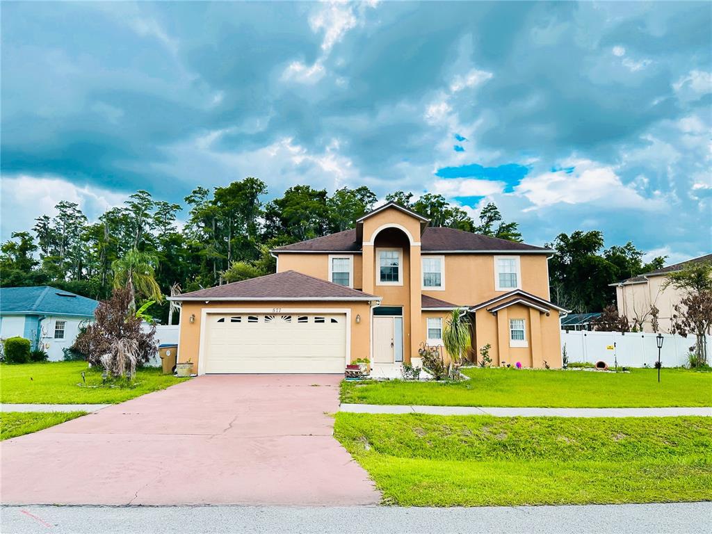 A two-story tan house with a two-car garage and a paved driveway — 577 PINEHURST COVE, KISSIMMEE, FL