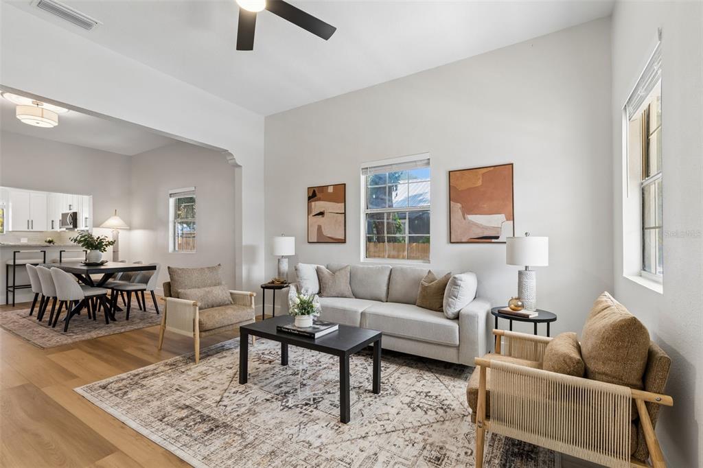 A bright living room features a light gray sofa, two armchairs, and a dining area — 3022 SANCHEZ STREET, TAMPA, FL