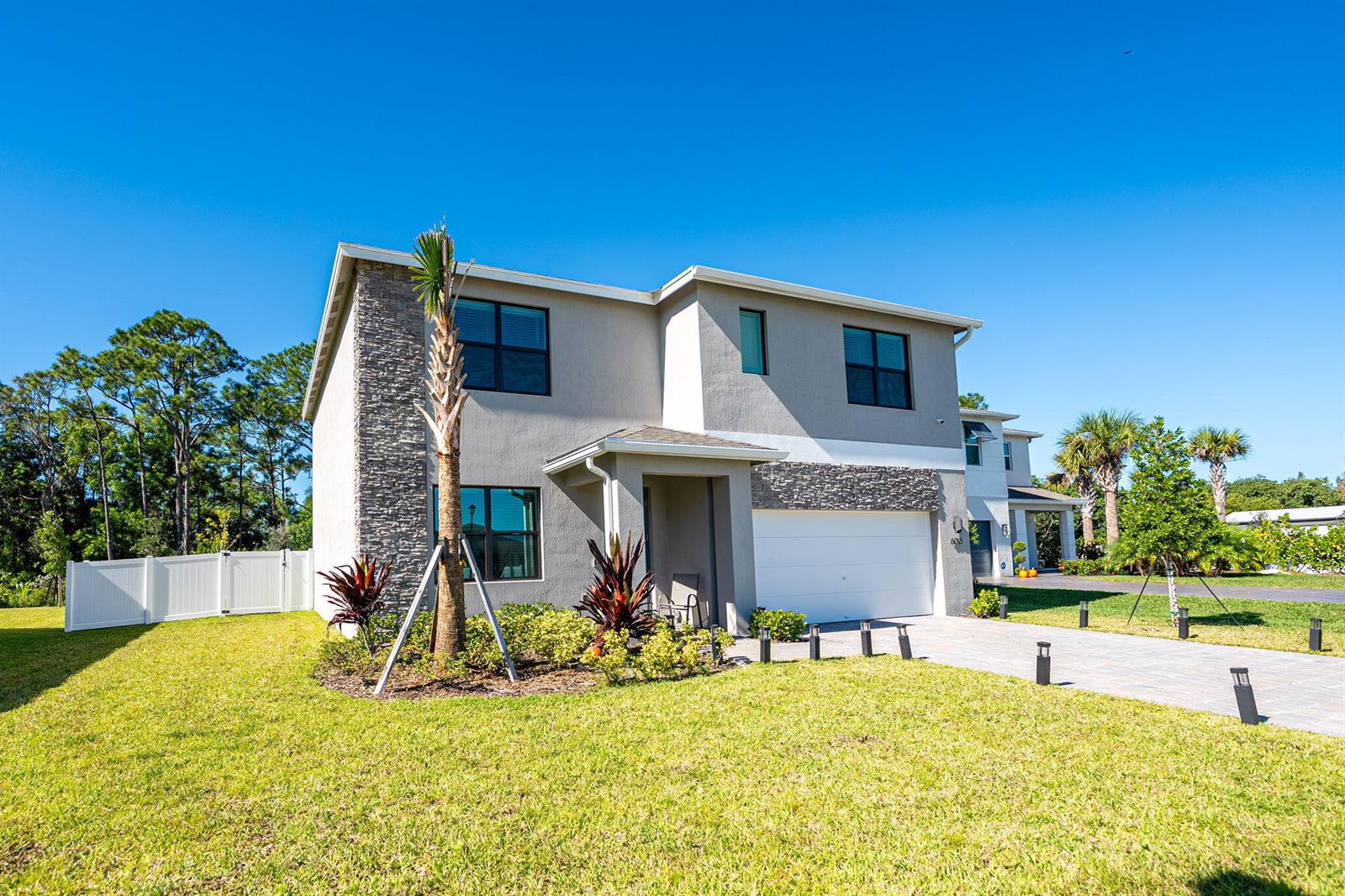 A two-story house with a stone facade, a white garage, and a palm tree — 6016 SE Violet Lane, Stuart FL 34997, STUART, FL