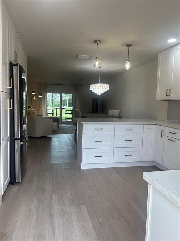 A kitchen with white cabinets and a central island overlooks a living area and patio — 1624 STICKNEY POINT ROAD UNIT 101, SARASOTA, FL