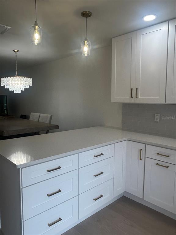 A kitchen features white shaker cabinets, quartz countertops, and pendant lighting over an island — 1624 STICKNEY POINT ROAD UNIT 101, SARASOTA, FL