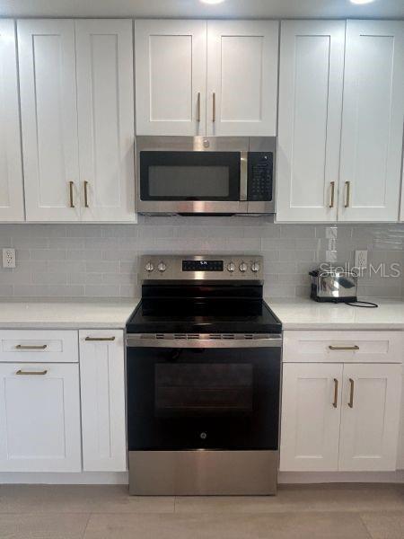 A kitchen features white cabinets, stainless steel appliances, and a light gray subway tile backsplash — 1624 STICKNEY POINT ROAD UNIT 101, SARASOTA, FL