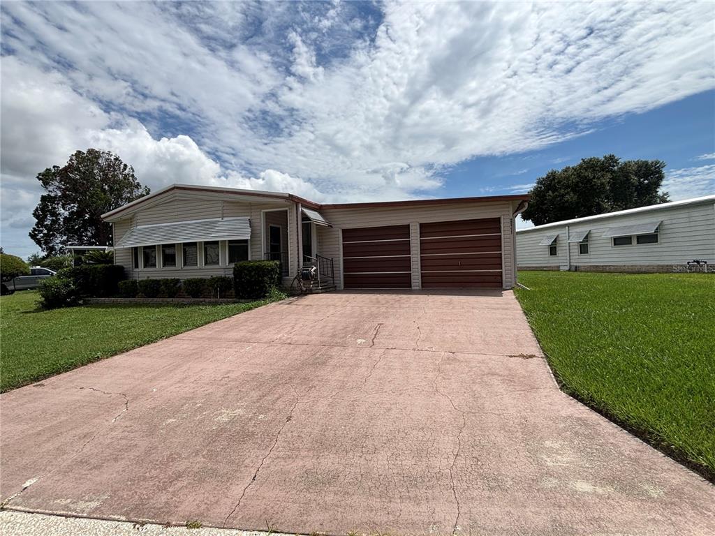 A single-story house with a two-car garage and a concrete driveway under a cloudy sky — 2541 AMYRIS COURT UNIT 611, ZELLWOOD, FL