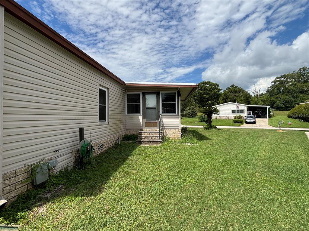A side view of a beige vinyl-sided house with a small porch and steps — 2541 AMYRIS COURT UNIT 611, ZELLWOOD, FL