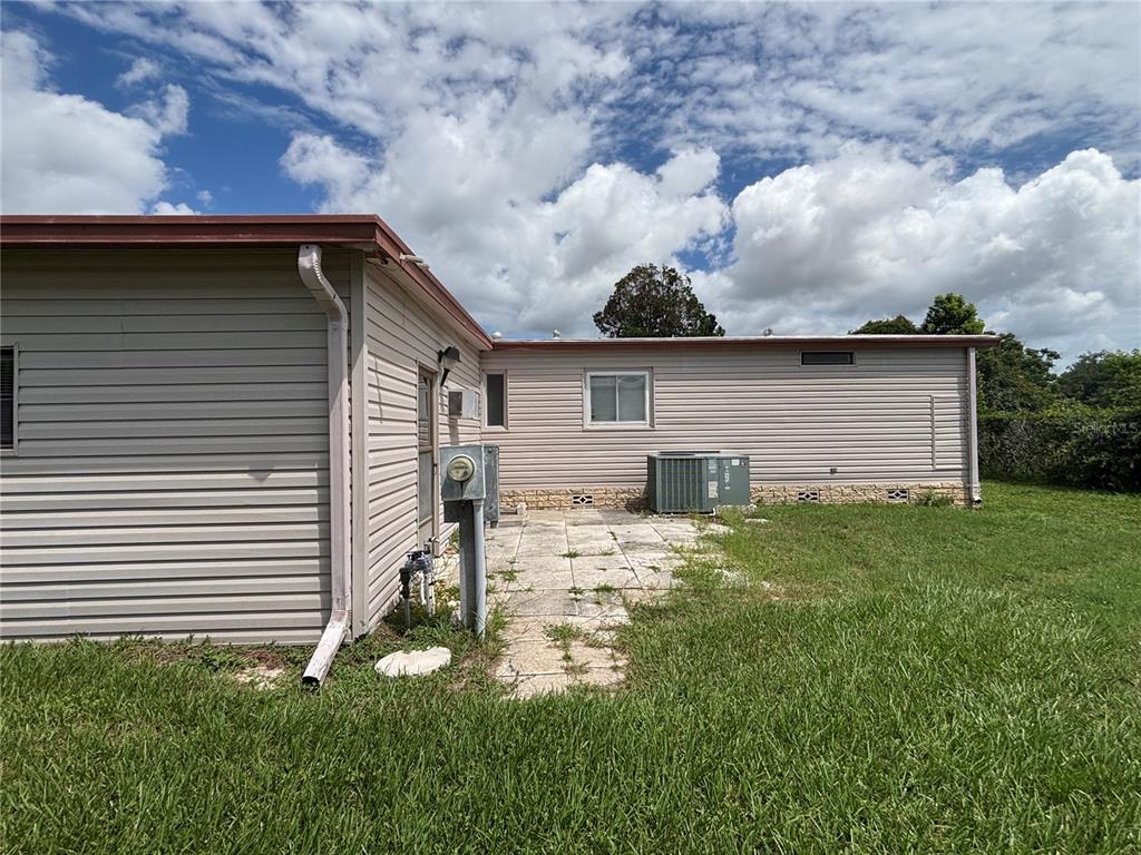 The exterior of a house features light-colored siding, a concrete patio, and an AC unit — 2541 AMYRIS COURT UNIT 611, ZELLWOOD, FL