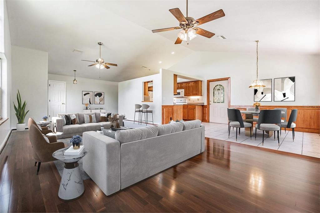 A spacious open-concept living and dining area features hardwood floors, vaulted ceilings, and wood wainscoting — 6536 NORTHLAKE DRIVE, ZEPHYRHILLS, FL