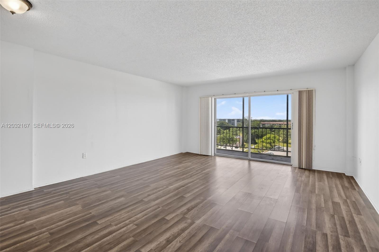 A screened-in balcony with a concrete floor overlooks a parking lot and trees — 4174 Inverrary Dr # 805, Lauderhill FL 33319, LAUDERHILL, FL