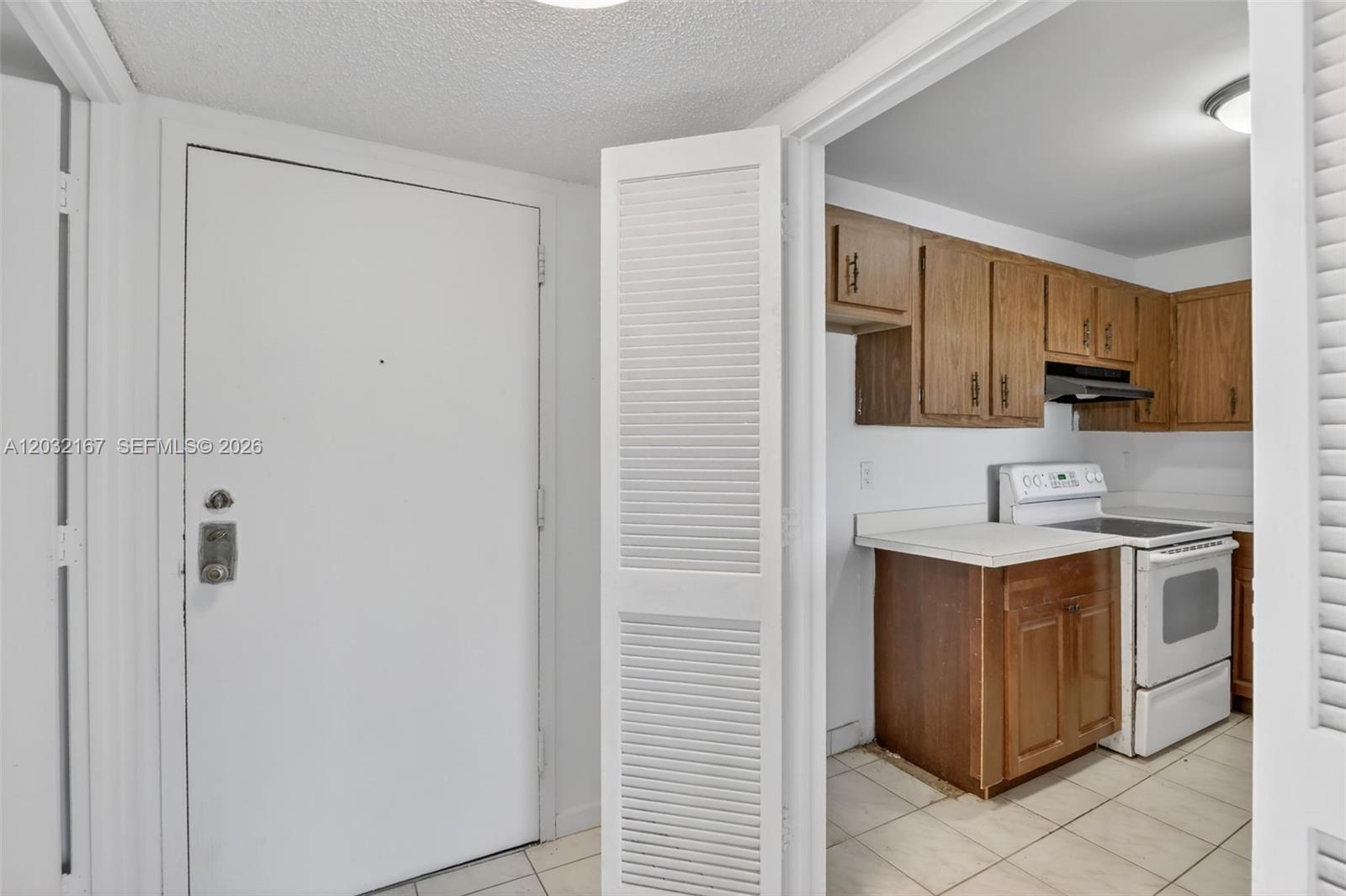 An empty living room features wood-look flooring, white walls, and a sliding glass balcony door — 4174 Inverrary Dr # 805, Lauderhill FL 33319, LAUDERHILL, FL