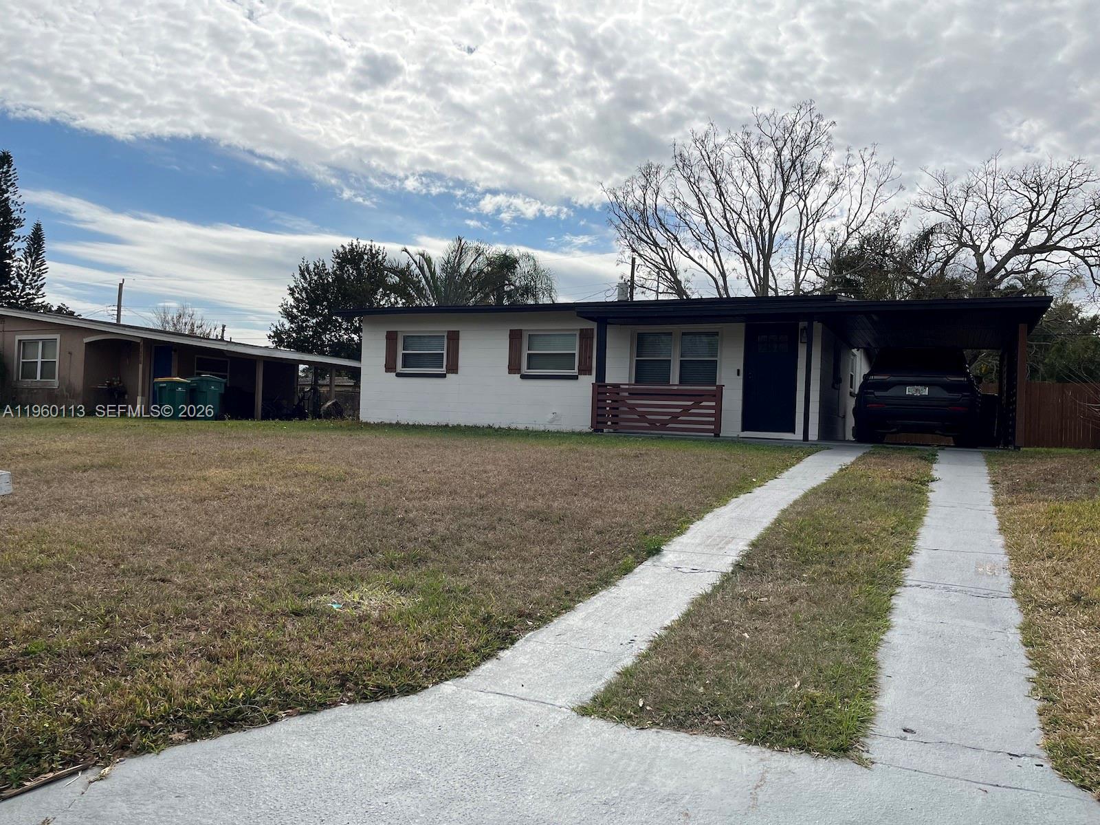 A single-story white house with a carport and a concrete driveway sits on a lawn — 2253 Dordon Drive, Melbourne FL 32935, MELBOURNE, FL
