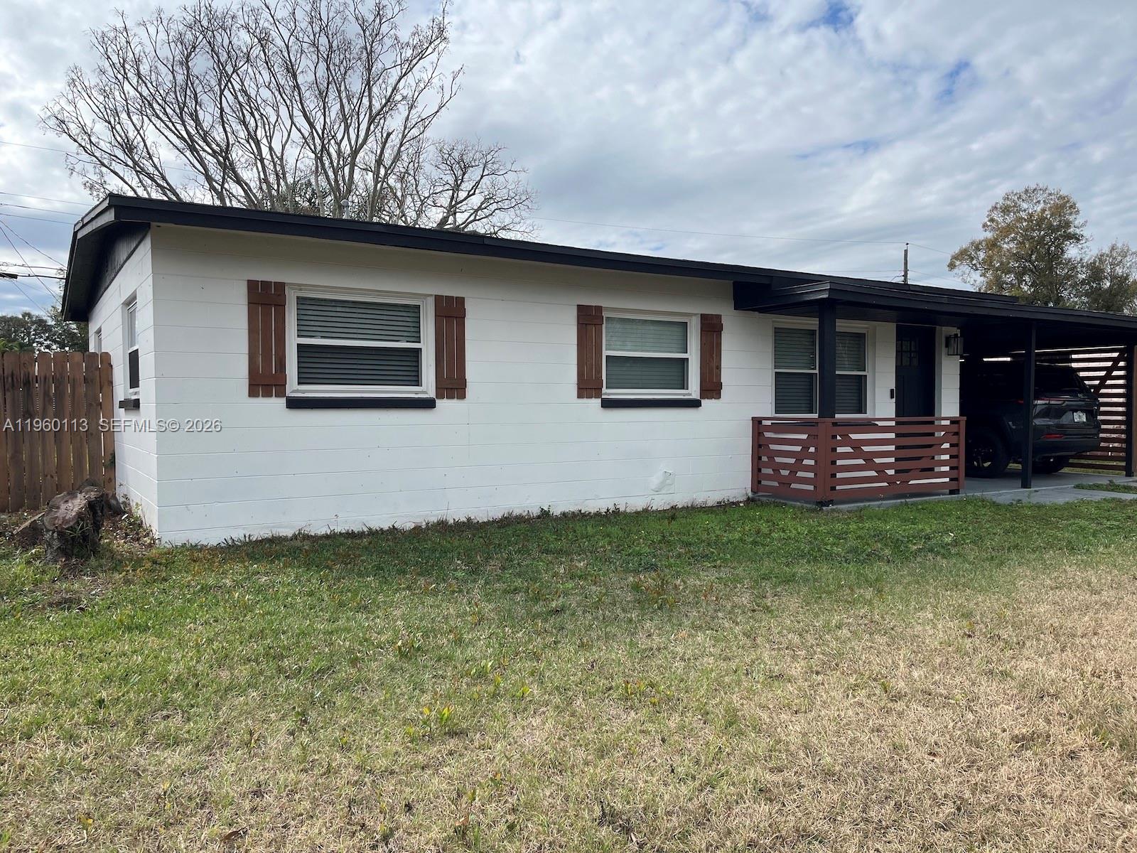 A white, single-story house features a carport, brown shutters, and a small wooden porch railing — 2253 Dordon Drive, Melbourne FL 32935, MELBOURNE, FL
