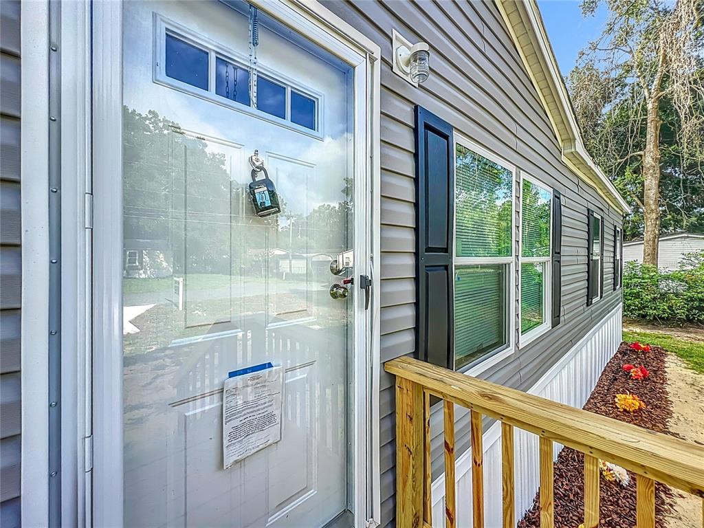 A white front door with a lockbox and notice sits on the side of a house — 8561 NW 13TH COURT, OCALA, FL