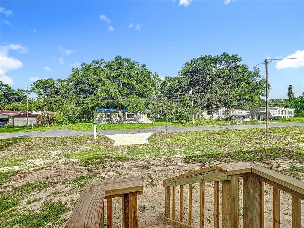 A view from a wooden deck looking across a sandy yard toward neighboring houses — 8561 NW 13TH COURT, OCALA, FL