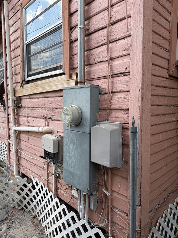 An exterior view of a pink wood-sided house featuring an electrical meter and utility boxes — 3612 N 23RD STREET, TAMPA, FL