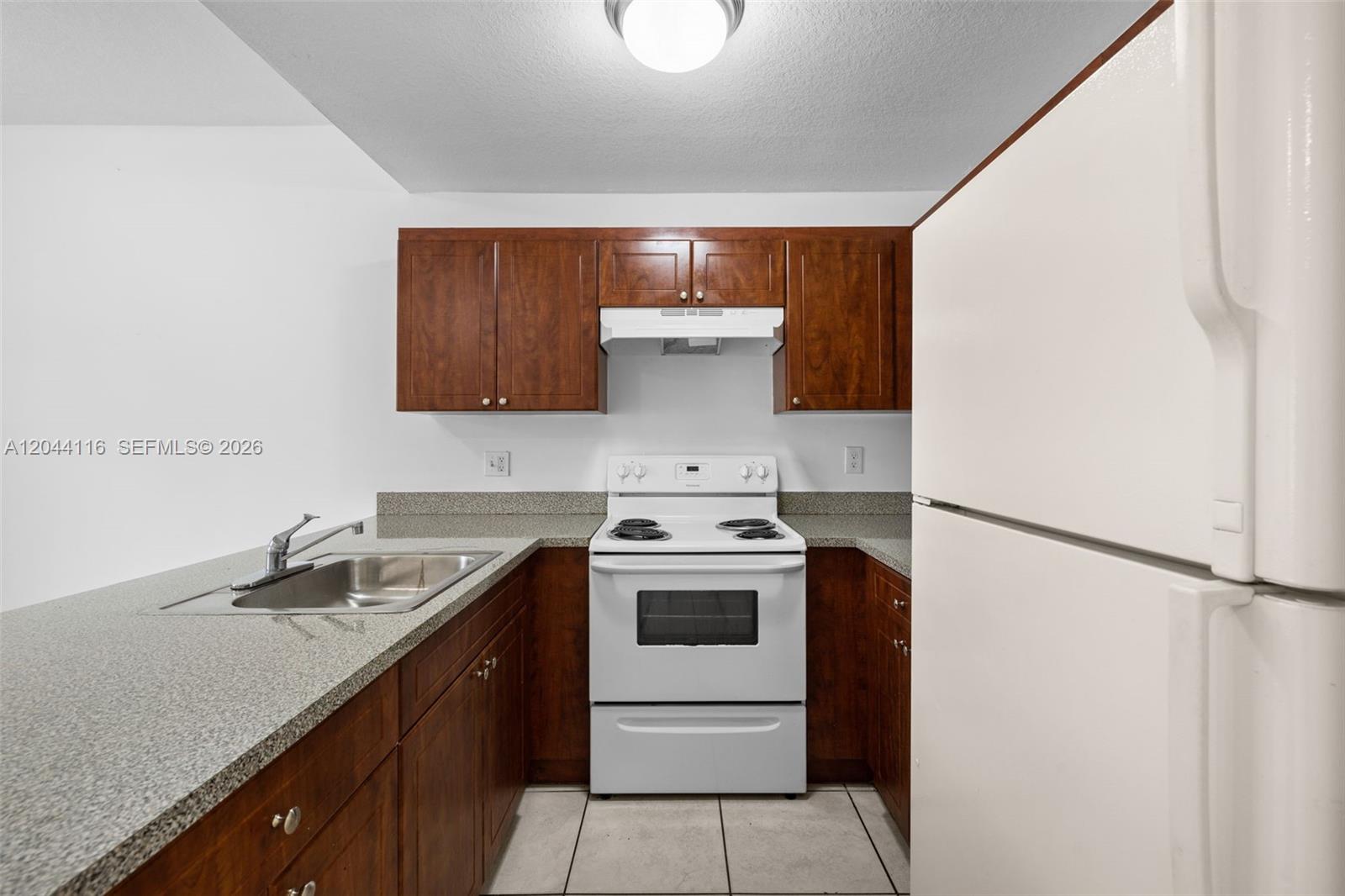 A kitchen features dark wood cabinets, granite countertops, a white stove, and a white refrigerator — 2421 W 78th St # 104, Hialeah FL 33016, HIALEAH, FL