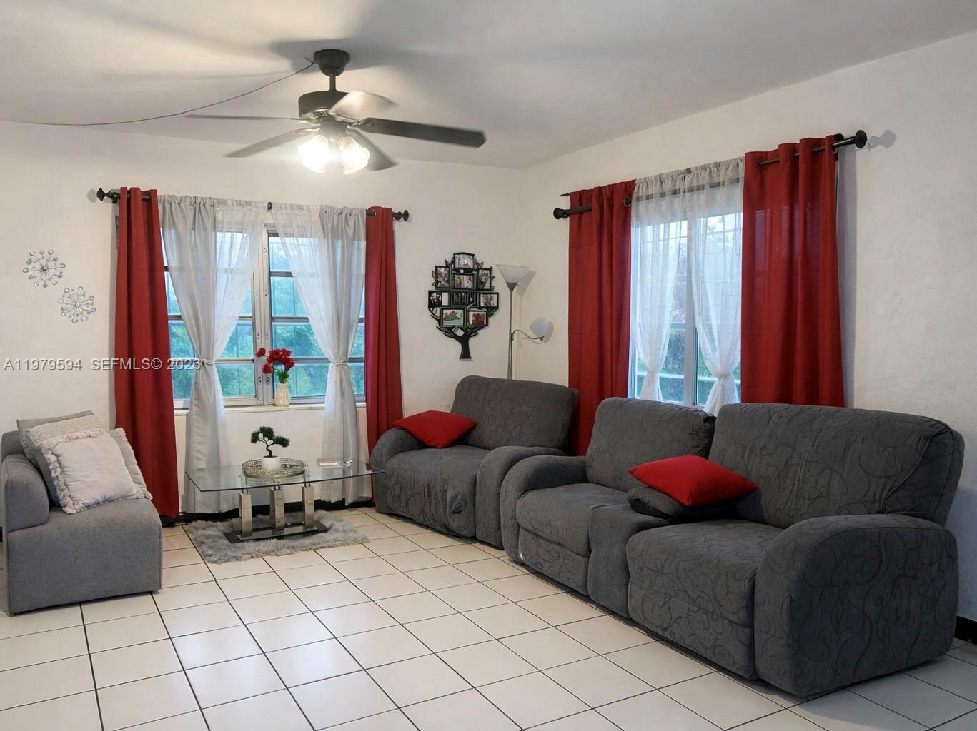 A living room features gray sofas, red curtains, a glass coffee table, and tile flooring — 631 Jann Ave, Opa-Locka FL 33054, OPA-LOCKA, FL