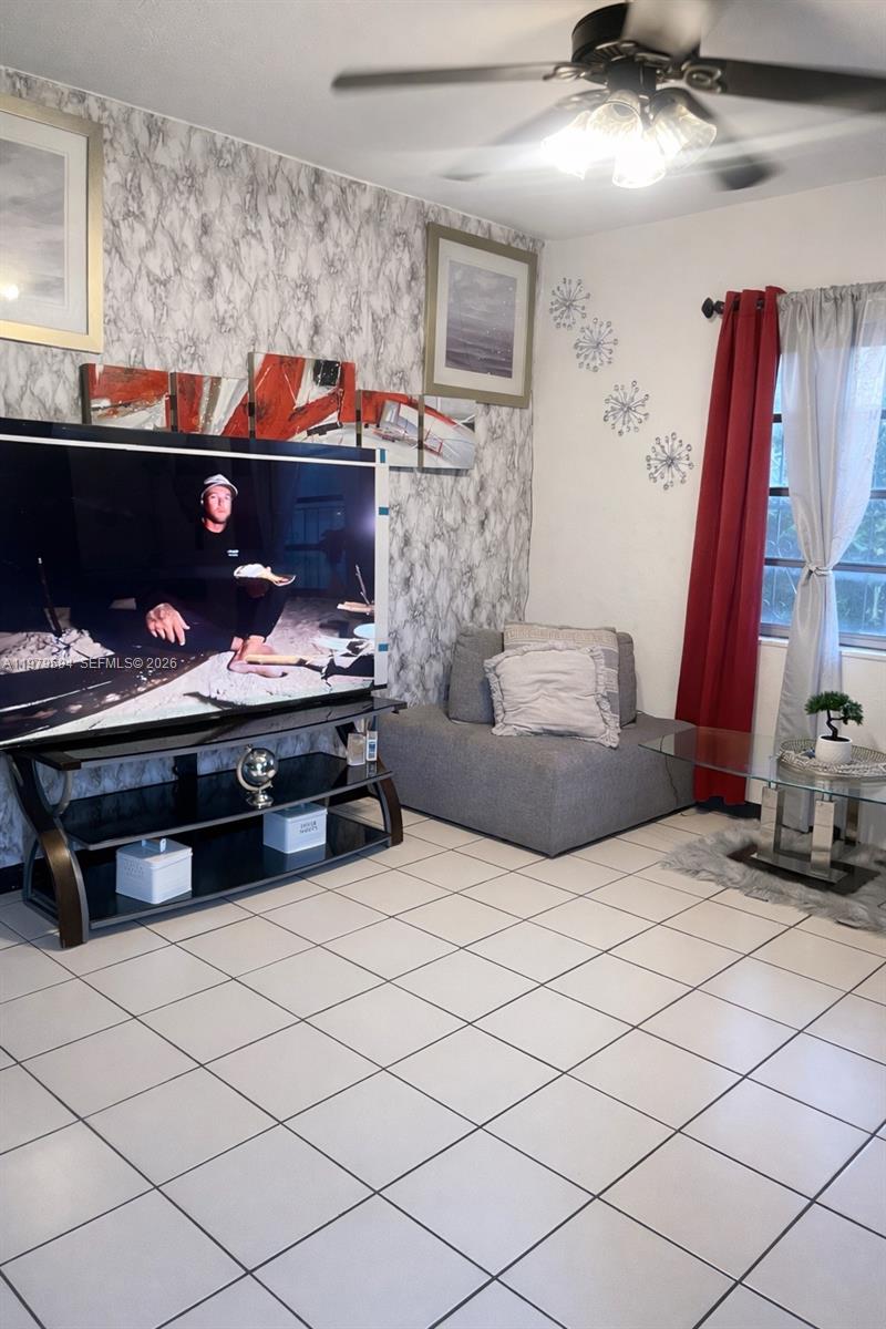 A living room features white tile floors, a marble-patterned accent wall, and a large television — 631 Jann Ave, Opa-Locka FL 33054, OPA-LOCKA, FL
