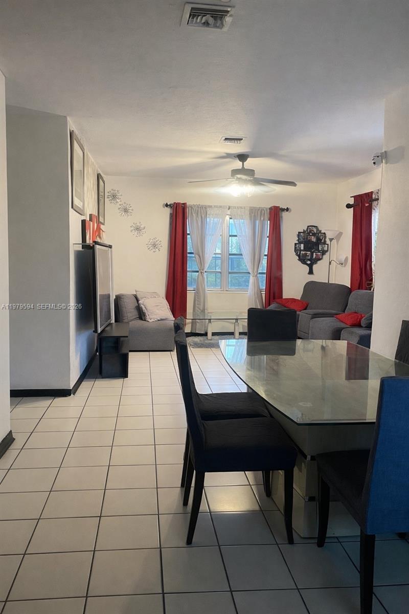 A dining area with a glass table and black chairs opens into a living room — 631 Jann Ave, Opa-Locka FL 33054, OPA-LOCKA, FL