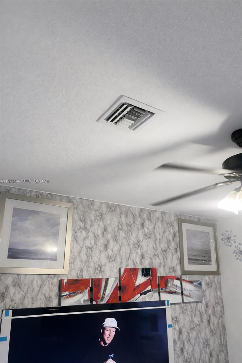 A room features a ceiling vent, a ceiling fan, framed wall art, and marble-patterned wallpaper — 631 Jann Ave, Opa-Locka FL 33054, OPA-LOCKA, FL