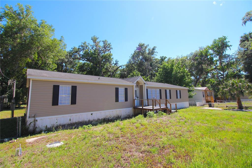 A single-story manufactured home with tan siding and a small wooden porch sits on grass — 9222 E RIVERBLUFF COURT, INVERNESS, FL