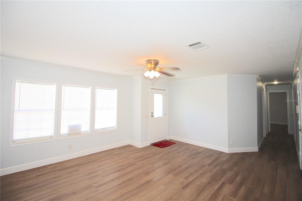 A living room features light blue walls, wood-look flooring, a ceiling fan, and three windows — 9222 E RIVERBLUFF COURT, INVERNESS, FL