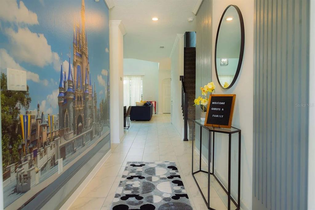 A hallway features a large Cinderella Castle wall mural, tiled floors, and a console table — 4294 PARAGRAPH DRIVE, KISSIMMEE, FL