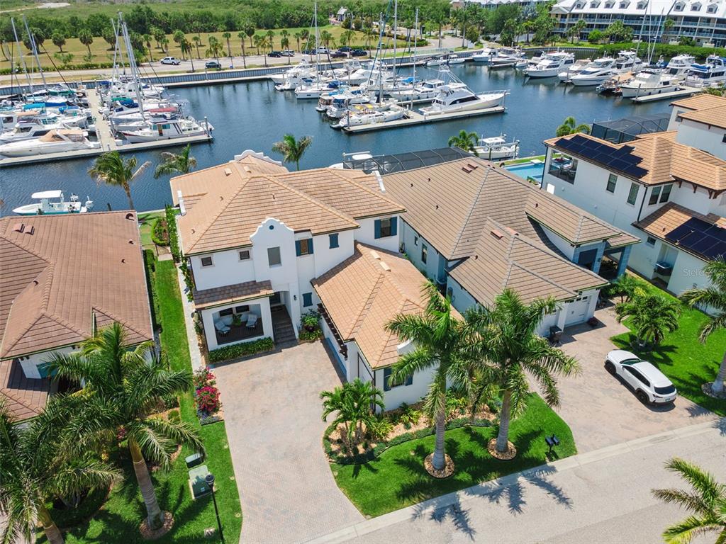 An aerial view shows a multi-story house with a tiled roof next to a boat marina — 3028 CHRISTOPHERS WATCH LANE, RUSKIN, FL