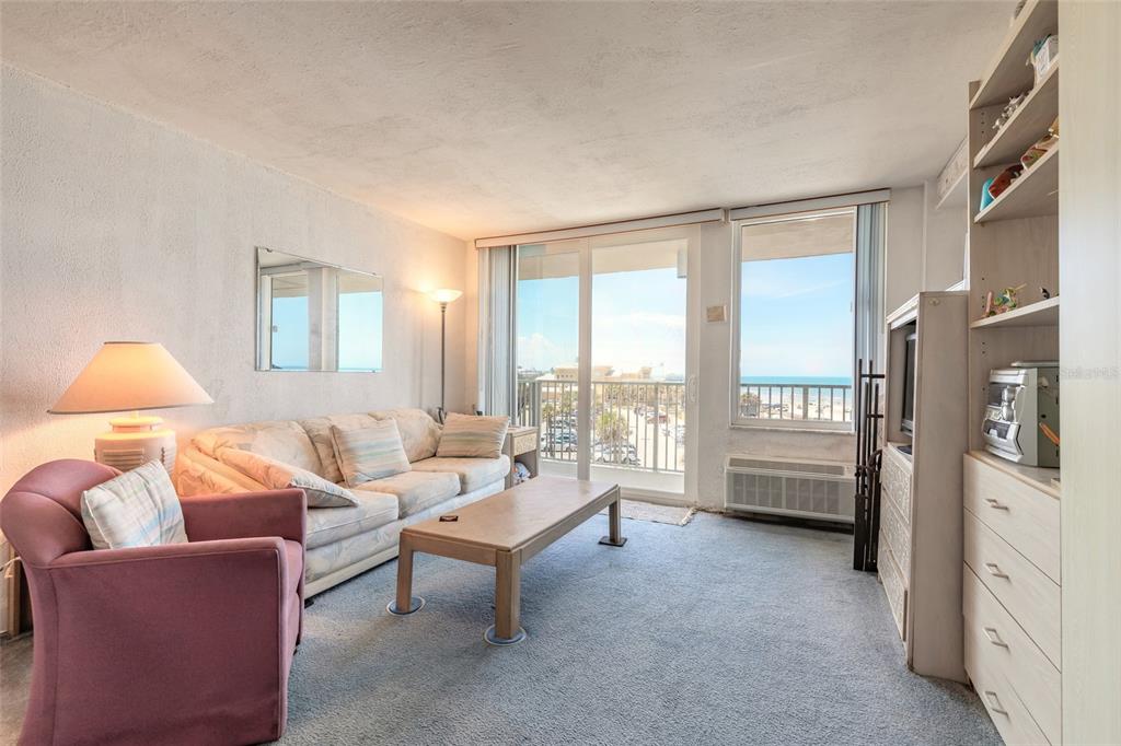 A living room with a sofa, armchair, coffee table, and a view of the ocean — 701 S ATLANTIC AVENUE UNIT 417, DAYTONA BEACH, FL