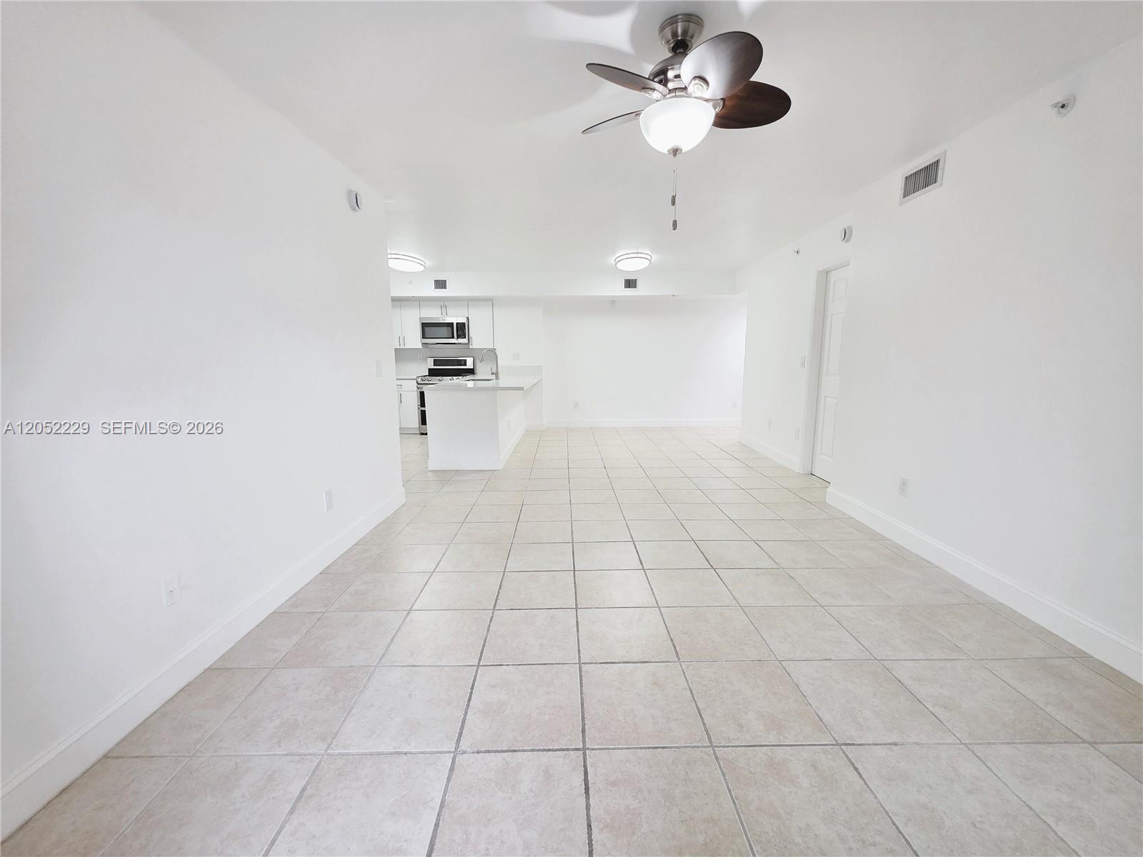 An open-concept living area features white walls, tile flooring, and a kitchen with white cabinetry — 2620 S University Dr # 111, Davie FL 33328, DAVIE, FL