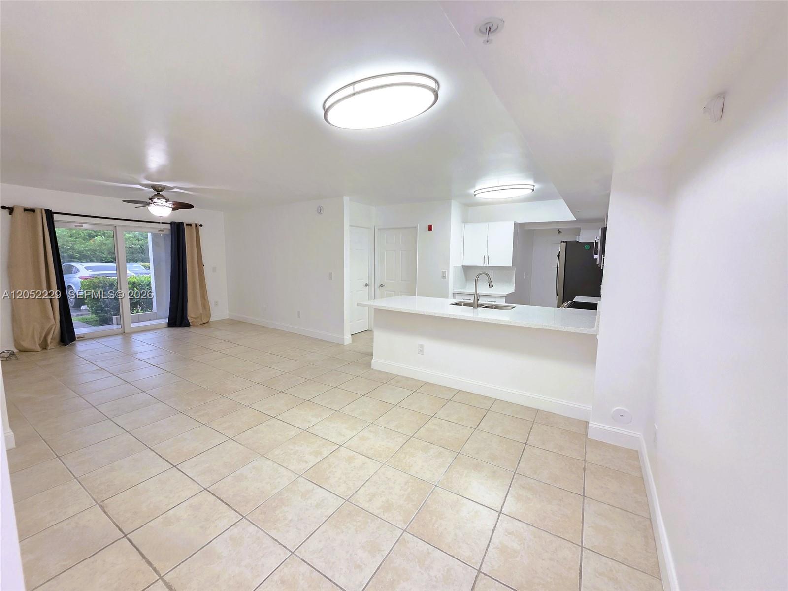 An open-concept living area features tile floors, a kitchen island, and sliding glass doors — 2620 S University Dr # 111, Davie FL 33328, DAVIE, FL