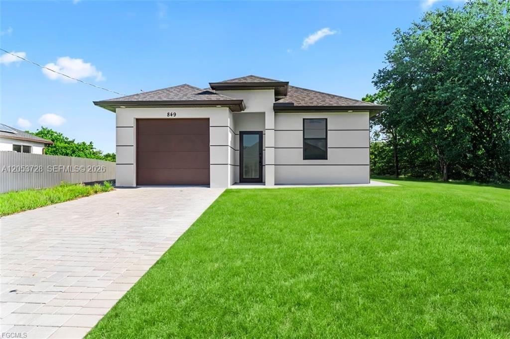 A modern, single-story house features a brown garage door, a glass front door, and horizontal trim — 849 E Wolverine, Lehigh Acres FL 33974, LEHIGH ACRES, FL