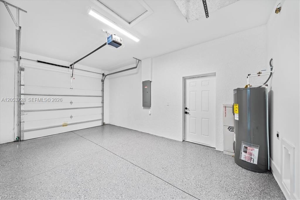 A clean garage features a white door, a water heater, and speckled epoxy flooring — 849 E Wolverine, Lehigh Acres FL 33974, LEHIGH ACRES, FL
