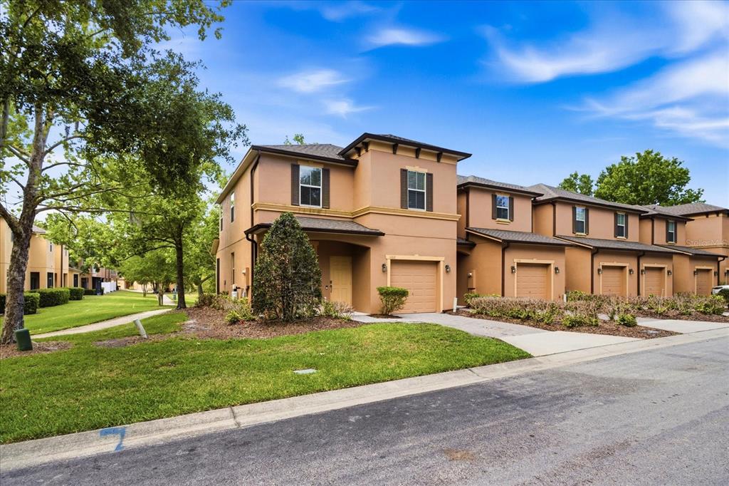 A two-story tan townhouse with a single-car garage and a grassy front yard — 1160 TWIN TREES LANE, SANFORD, FL