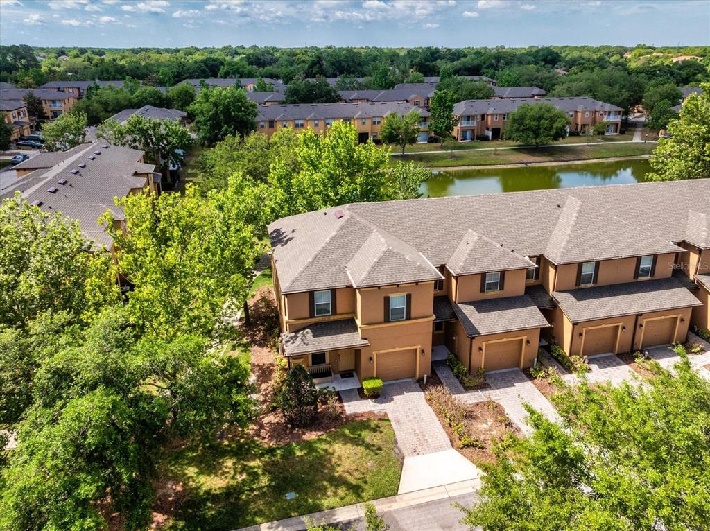 An aerial view shows a multi-unit townhouse complex with tan stucco exteriors and brown roofs — 1160 TWIN TREES LANE, SANFORD, FL