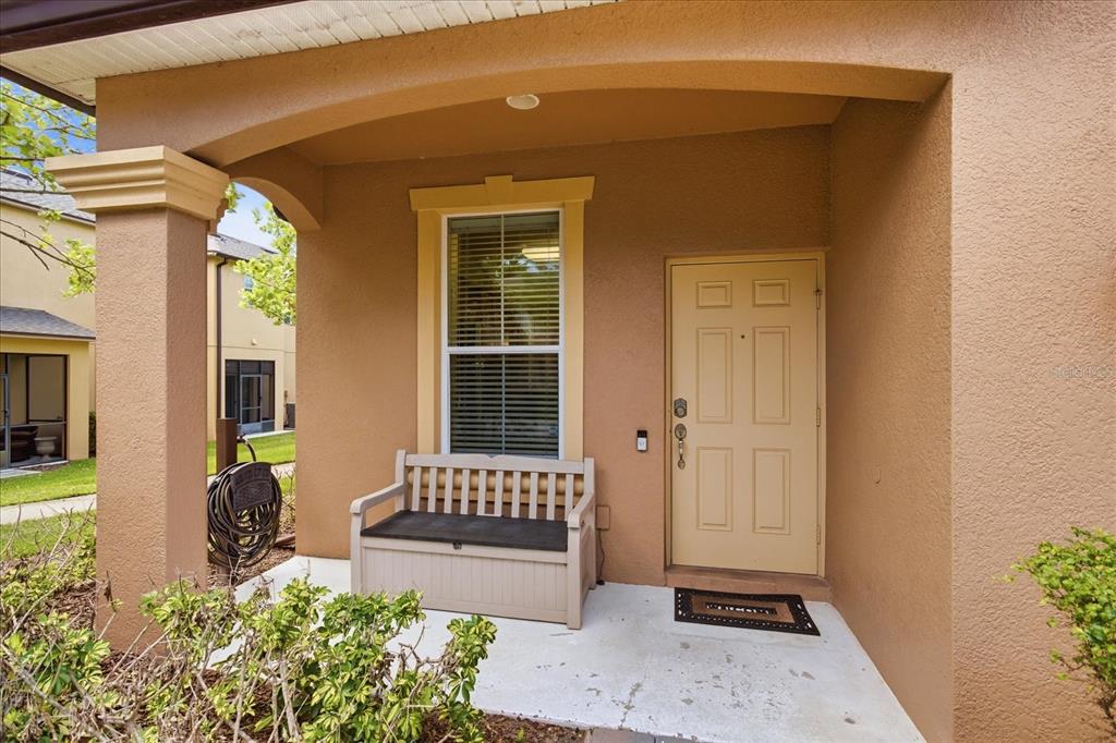 A covered front porch features a beige door, a window, and a storage bench — 1160 TWIN TREES LANE, SANFORD, FL