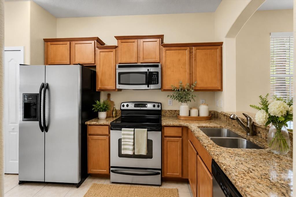 A kitchen features wood cabinets, granite countertops, stainless steel appliances, and a double basin sink — 1160 TWIN TREES LANE, SANFORD, FL