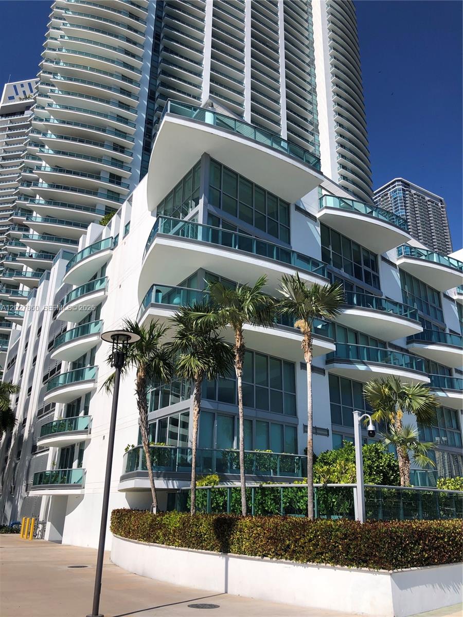 A low-angle view of a modern white high-rise building with glass balconies and palm trees — 1331 Brickell Bay Dr # 48, Miami FL 33131, MIAMI, FL