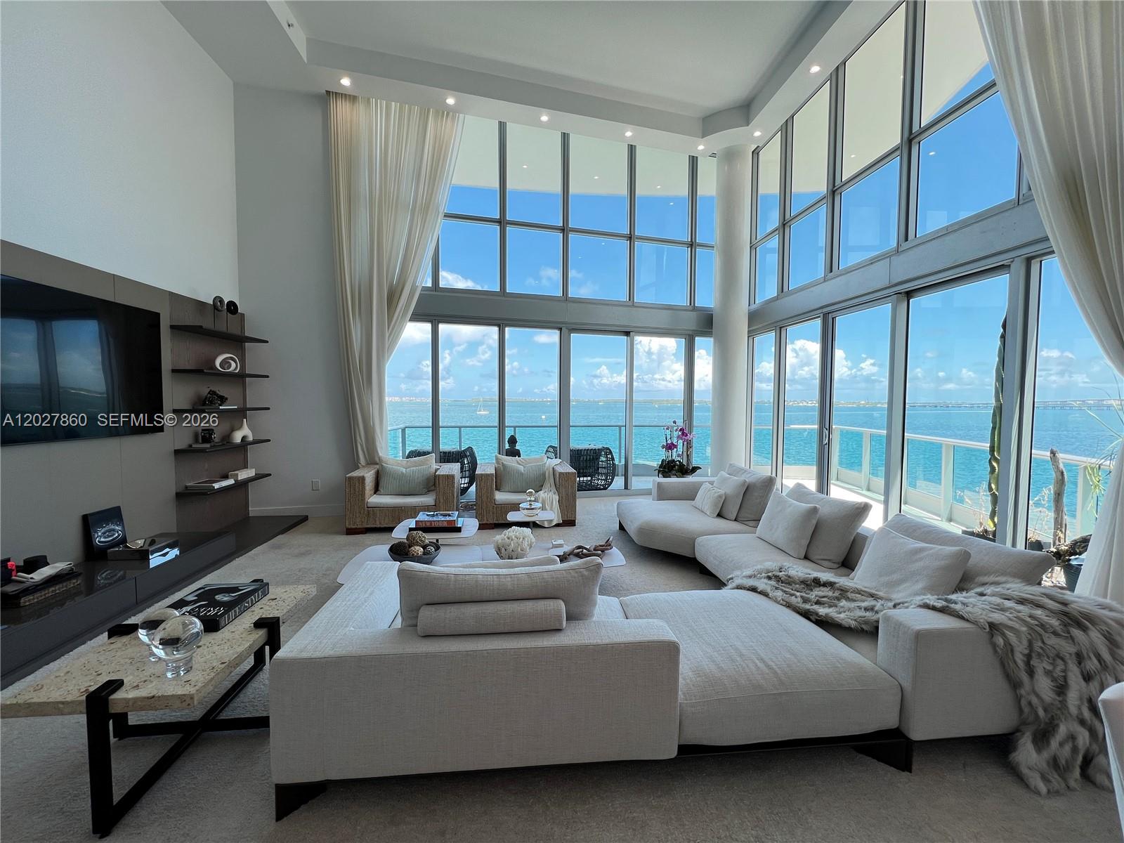 A modern living room features floor-to-ceiling windows with expansive ocean views and neutral furniture — 1331 Brickell Bay Dr # 48, Miami FL 33131, MIAMI, FL