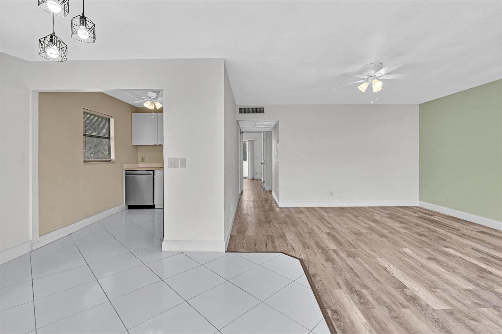An interior view shows a kitchen with tiled floors adjacent to a living area with wood-look flooring — 365 Flanders # H, Delray Beach FL 33484, DELRAY BEACH, FL