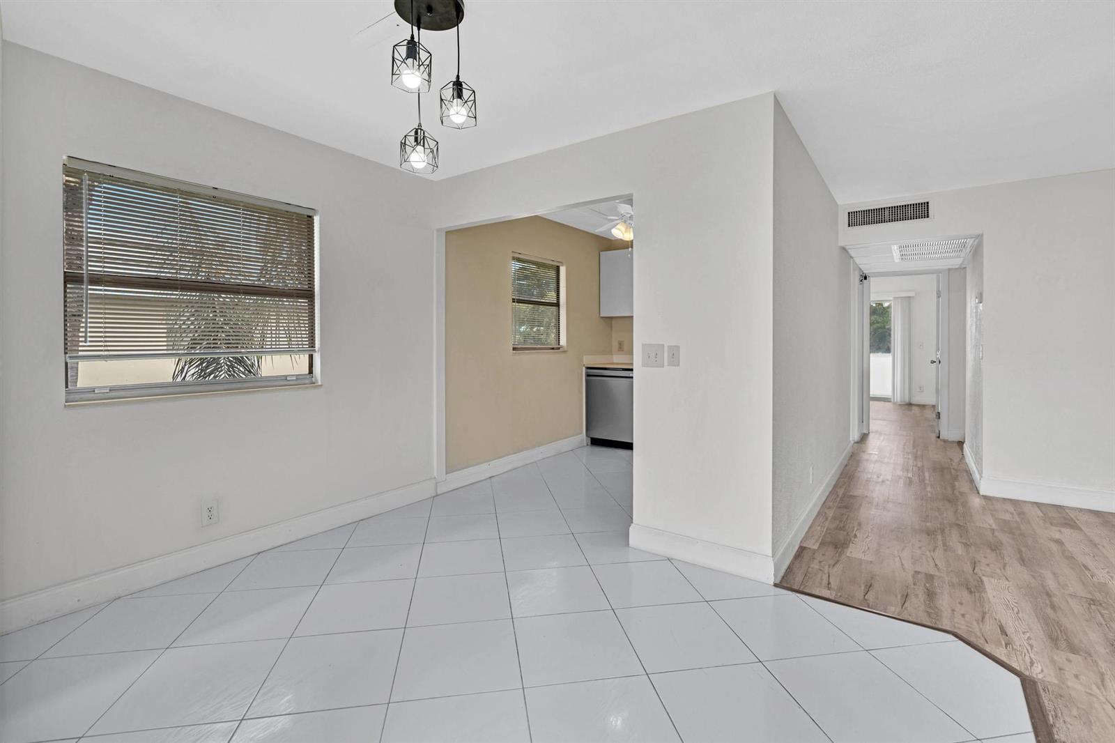 A dining area with white tile floors leads into a kitchen and a hallway — 365 Flanders # H, Delray Beach FL 33484, DELRAY BEACH, FL