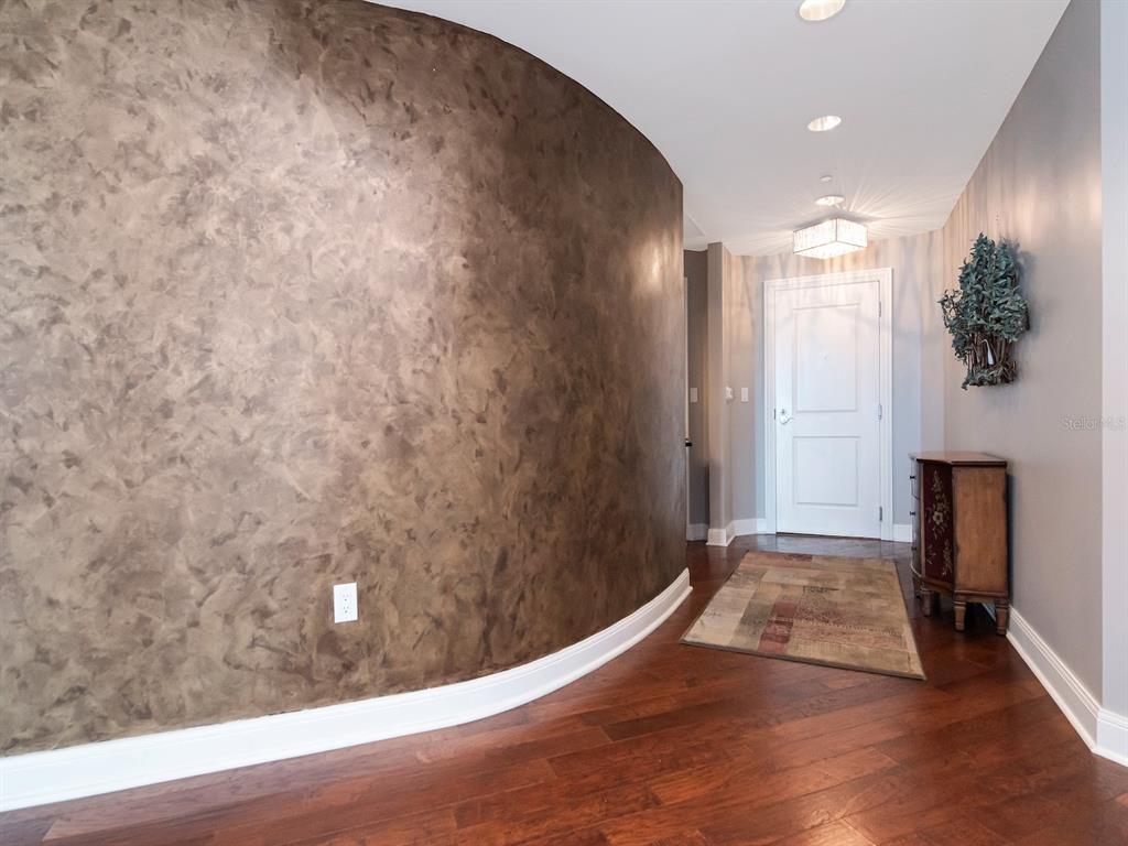 A curved wall with a faux finish leads to a white door in a foyer — 450 KNIGHTS RUN AVENUE UNIT 1501, TAMPA, FL