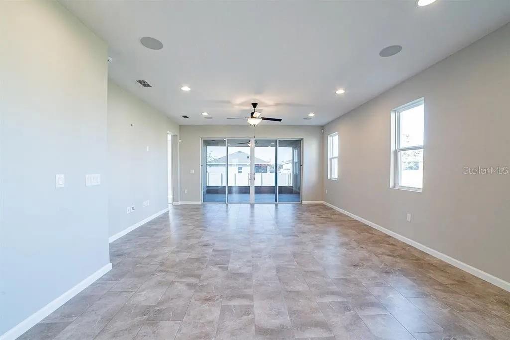 A spacious living room features light gray walls, tile flooring, recessed lighting, and sliding glass doors — 203 SANGMON COURT, GROVELAND, FL