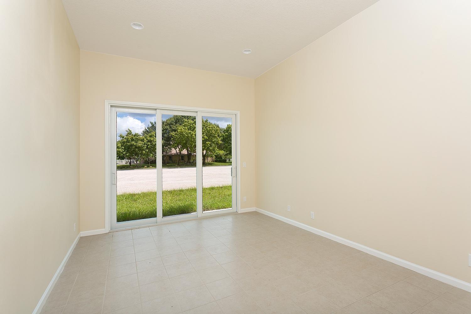 An empty room with beige walls, tile flooring, and a sliding glass door to outside — 2088 Appaloosa Trail, Wellington FL, WELLINGTON, FL