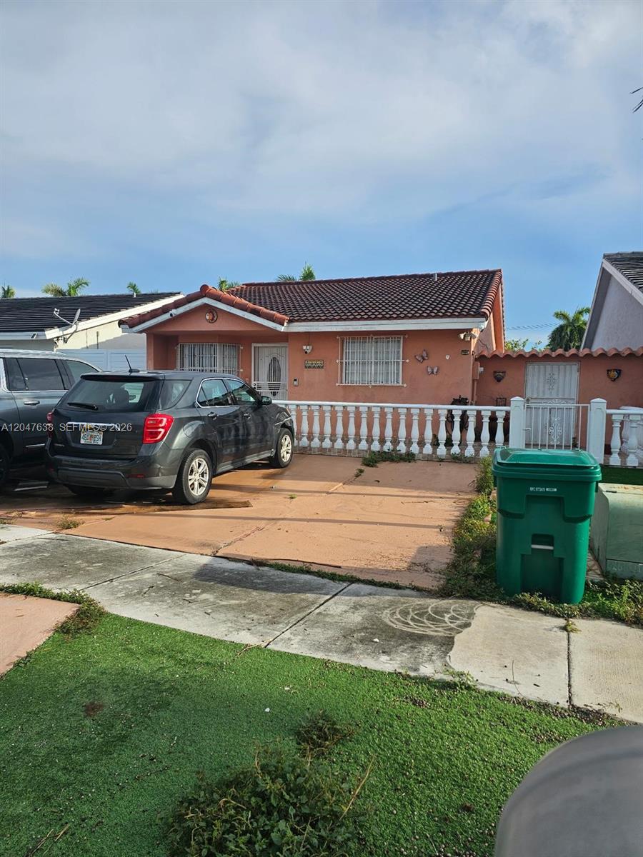 A single-story peach-colored house with a tiled roof, a driveway, and a white balustrade fence — 8805 NW 113th St, Hialeah Gardens FL 33018, HIALEAH GARDENS, FL