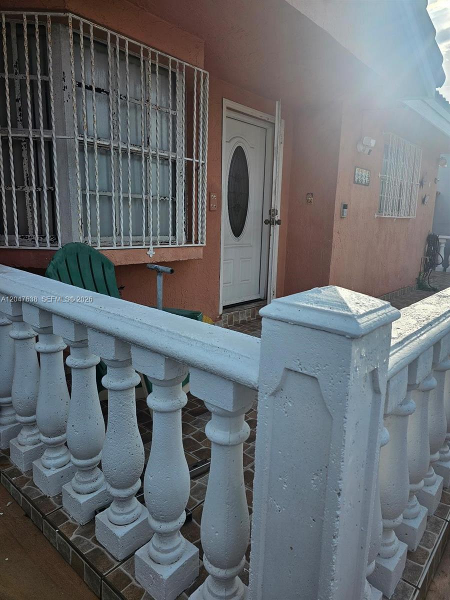 A peach-colored house exterior features a white front door, security bars, and a balustrade railing — 8805 NW 113th St, Hialeah Gardens FL 33018, HIALEAH GARDENS, FL